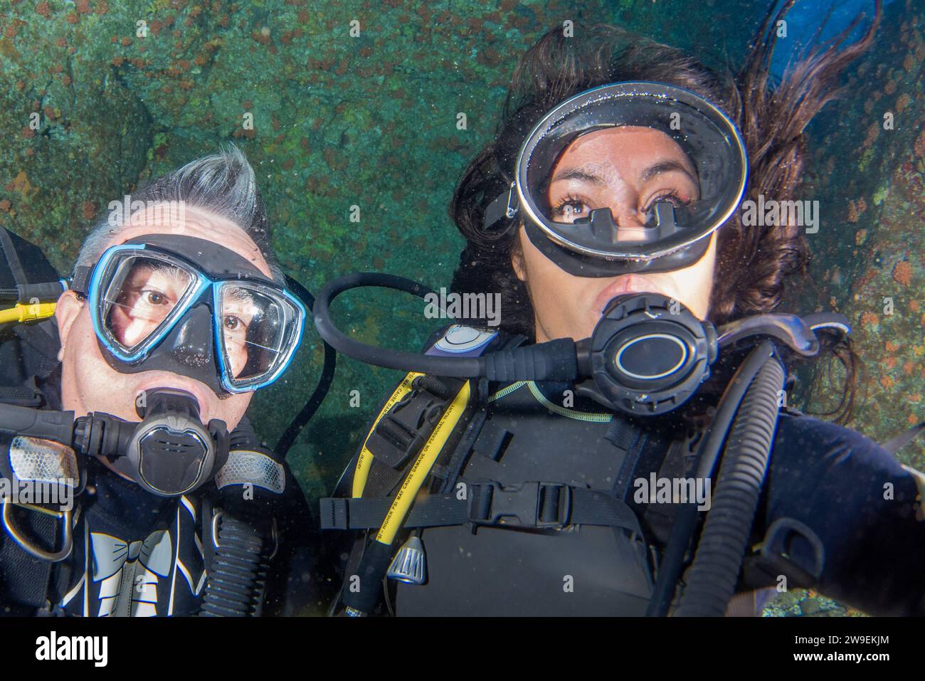 A beautiful black long hair latina scuba diver diving underwater with
