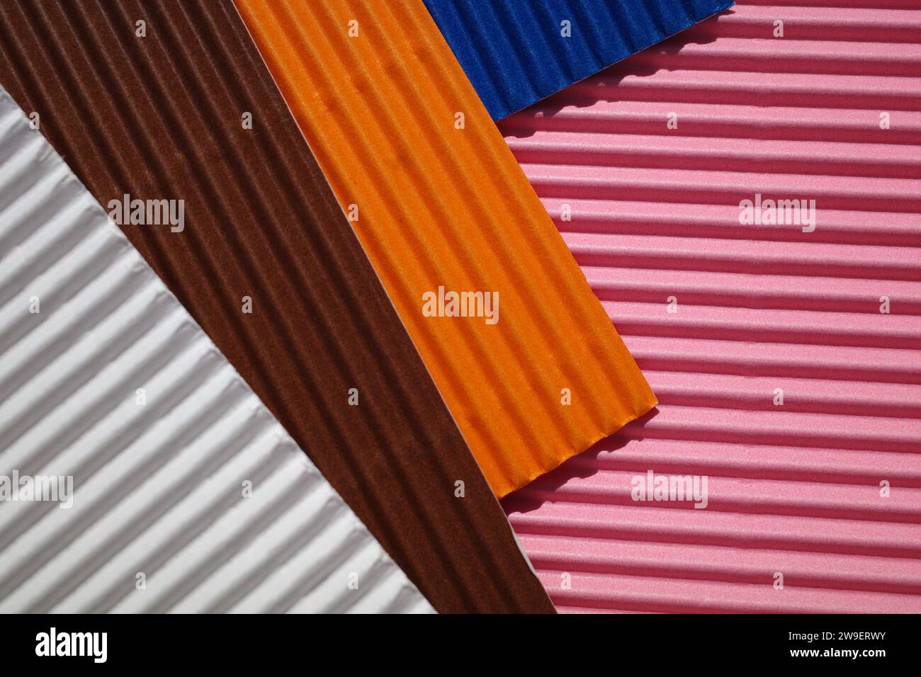Horizontally and diagonally ribbed cardboard with the colors pink, white,  orange, brown, blue. Meant as background Stock Photo