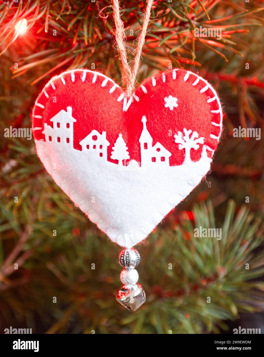 Homemade handicraft felt Christmas tree decorations on a tree with lights, a heart shaped red and white snow scene Stock Photo