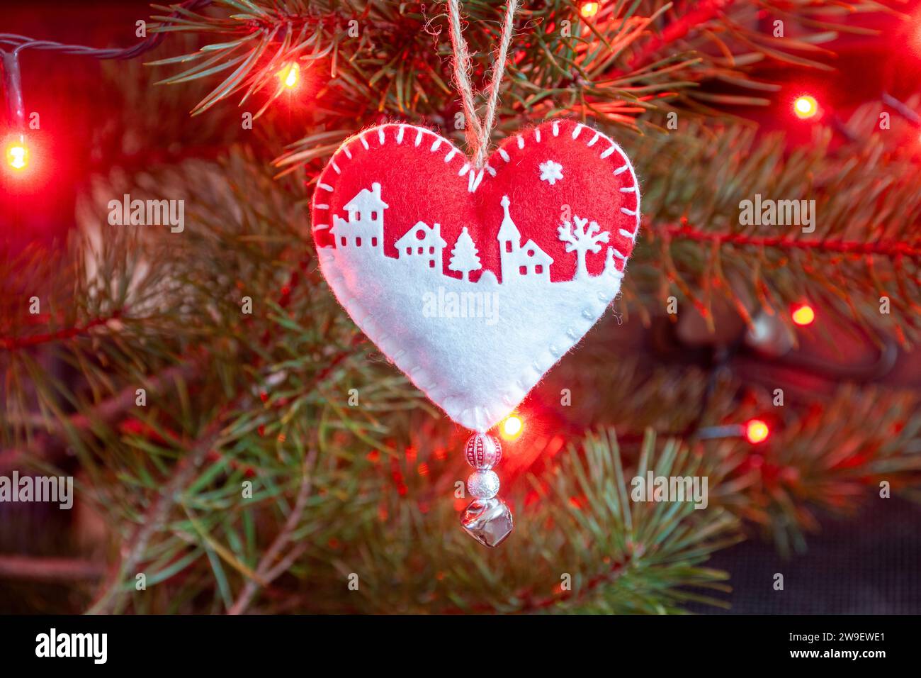 Homemade handicraft felt Christmas tree decorations on a tree with lights, a heart shaped red and white snow scene Stock Photo