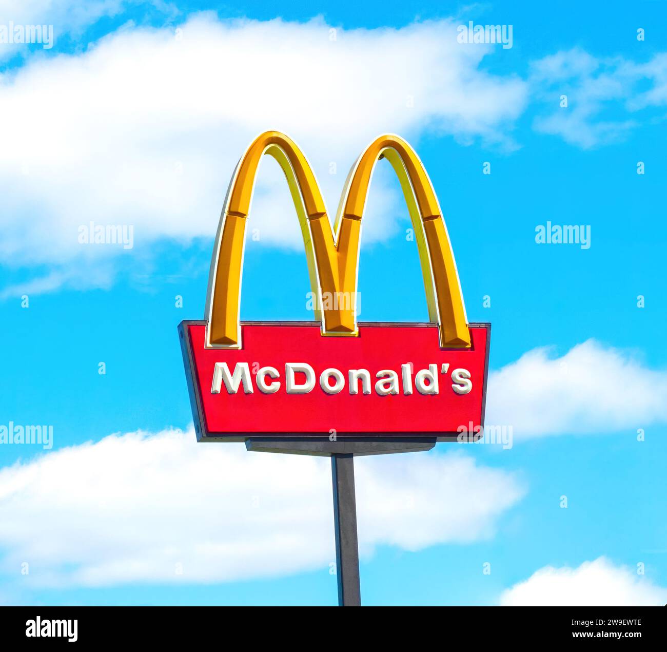 OCALA, FLORIDA USA - OCTOBER 14, 2023 McDonalds logo blue sky background with white clouds. Yellow golden arch iconic sign tall as seen from busy road Stock Photo