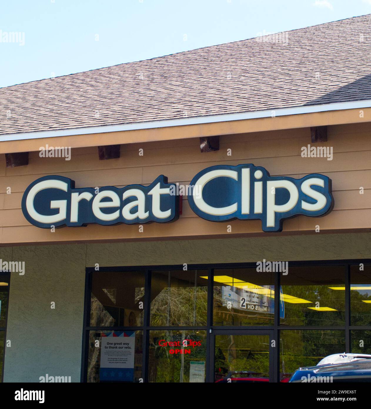 Great Clips hair salon Exterior facade sign signage above entrance in strip mall haircut location. They provide haircuts to men, women and kids. Blue Stock Photo