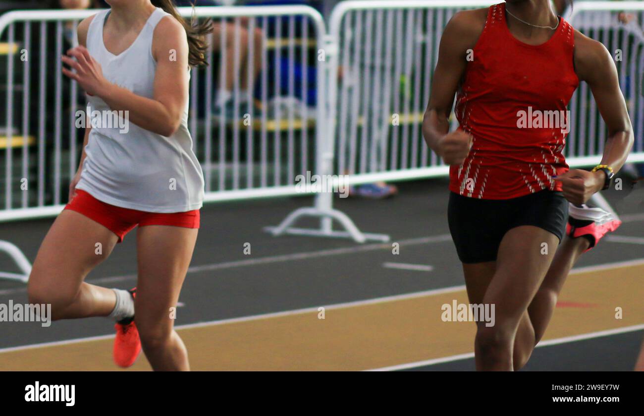 Front view of two high school track runners competing in an indoor