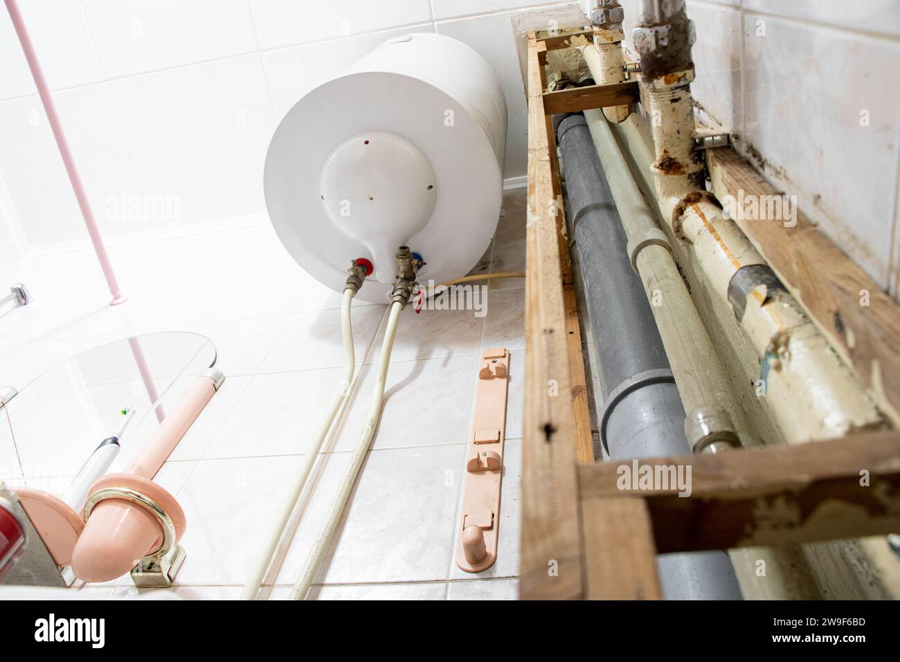 Water heater and pipes in a residential apartment after replacing the pipe with a new one, bathroom and plumbing repairs Stock Photo