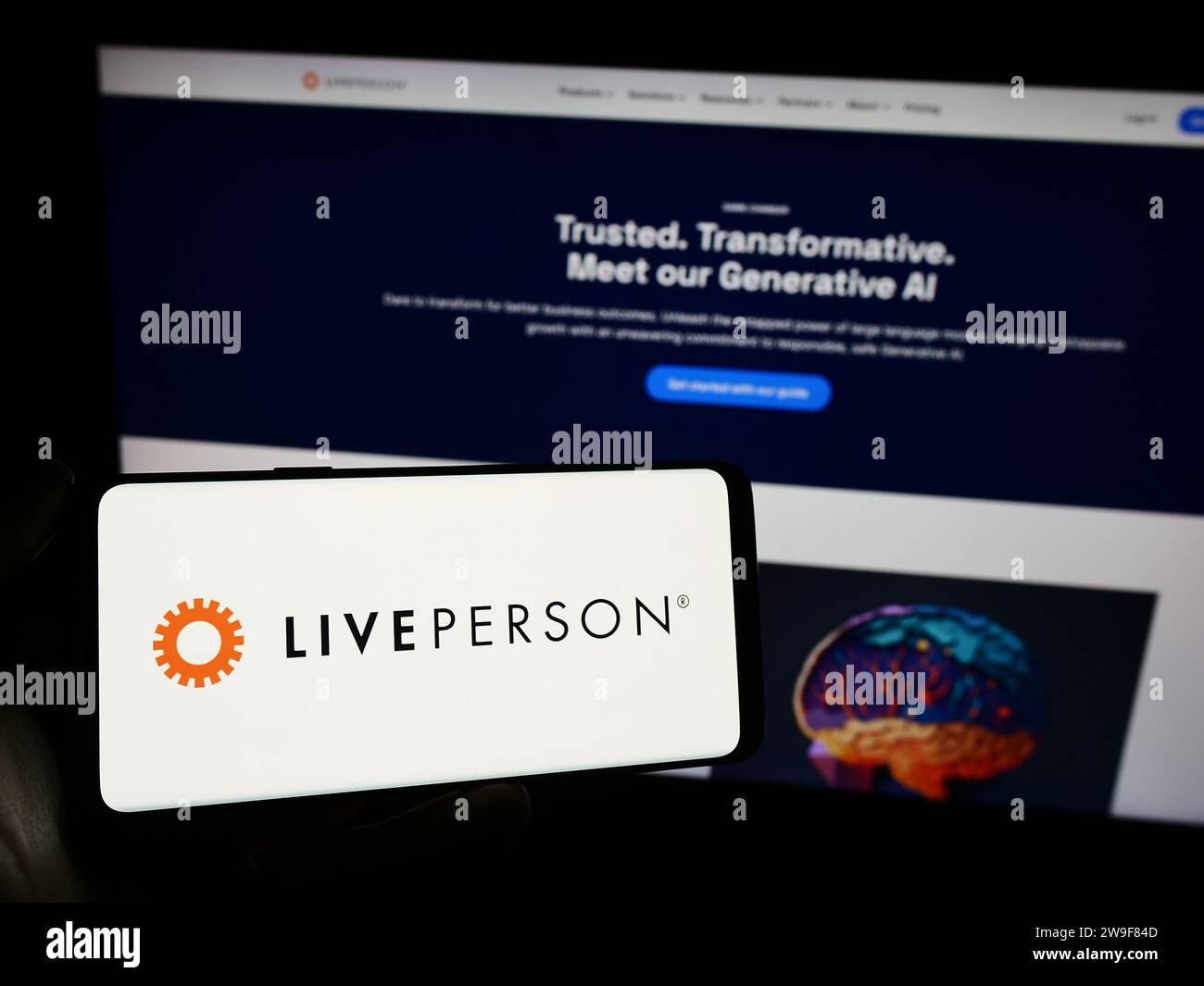 Person holding cellphone with logo of conversational commerce company LivePerson Inc. in front of business webpage. Focus on phone display. Stock Photo