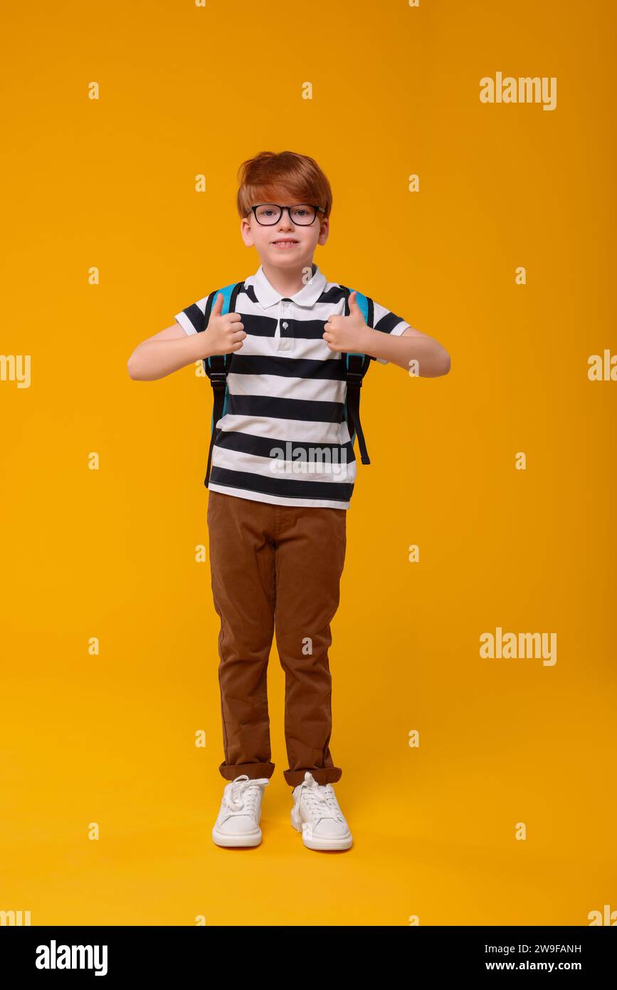 Happy schoolboy showing thumbs up on orange background Stock Photo - Alamy