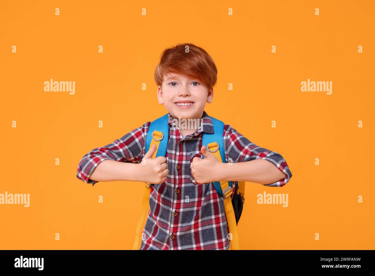 Happy schoolboy showing thumbs up on orange background Stock Photo - Alamy