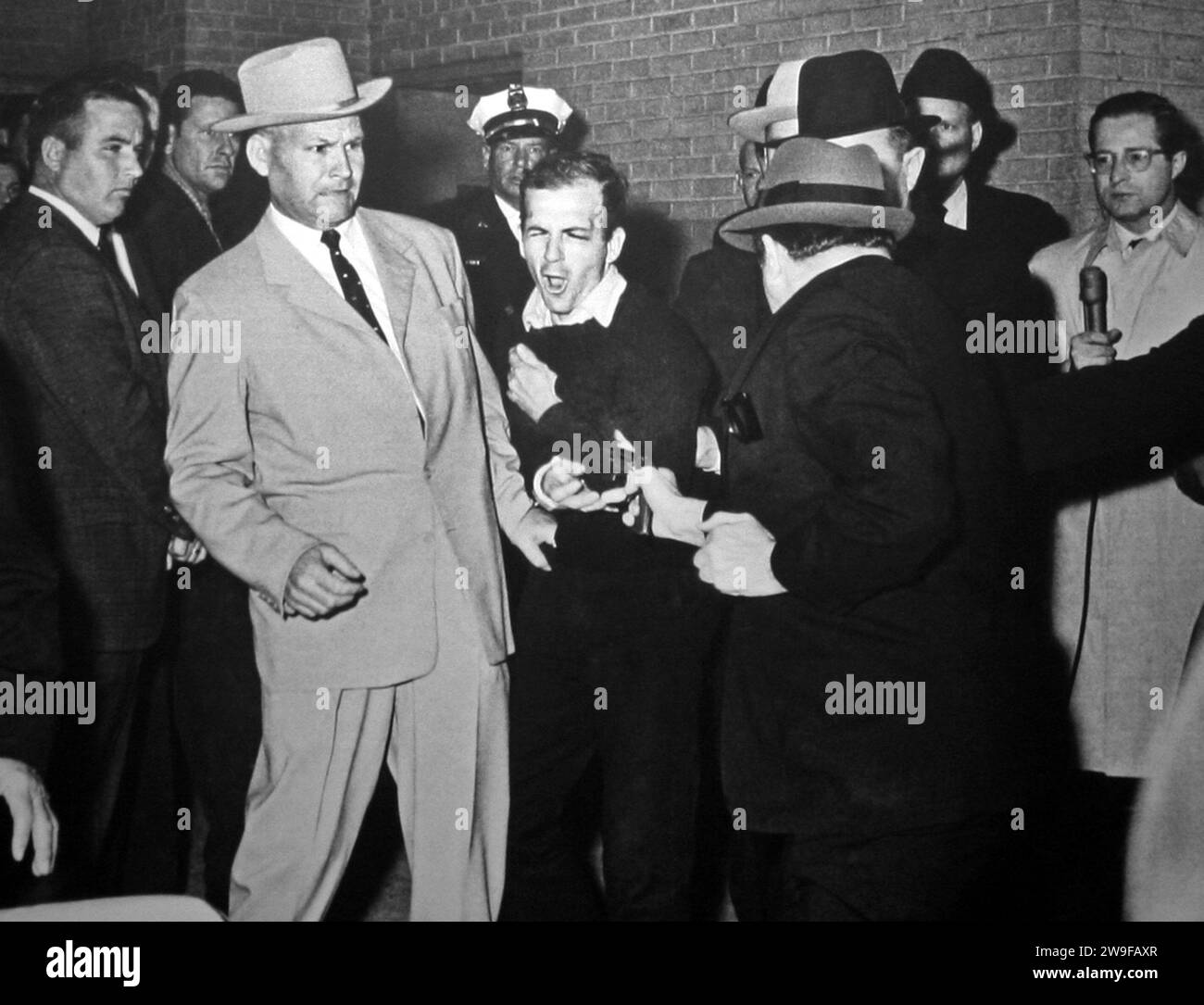 Jack Ruby (52) shoots Lee Harvey Oswald (24). Winner of the 1964 Pulitzer Prize for Photography by Robert H. Jackson Ruby shooting Oswald, who is being escorted by Dallas police. Detective Jim Leavelle is wearing the tan suit. L. C. Graves is with the black hat. Stock Photo