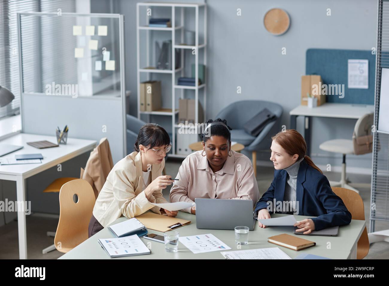 Three Female Colleagues Working on Business Report Stock Photo