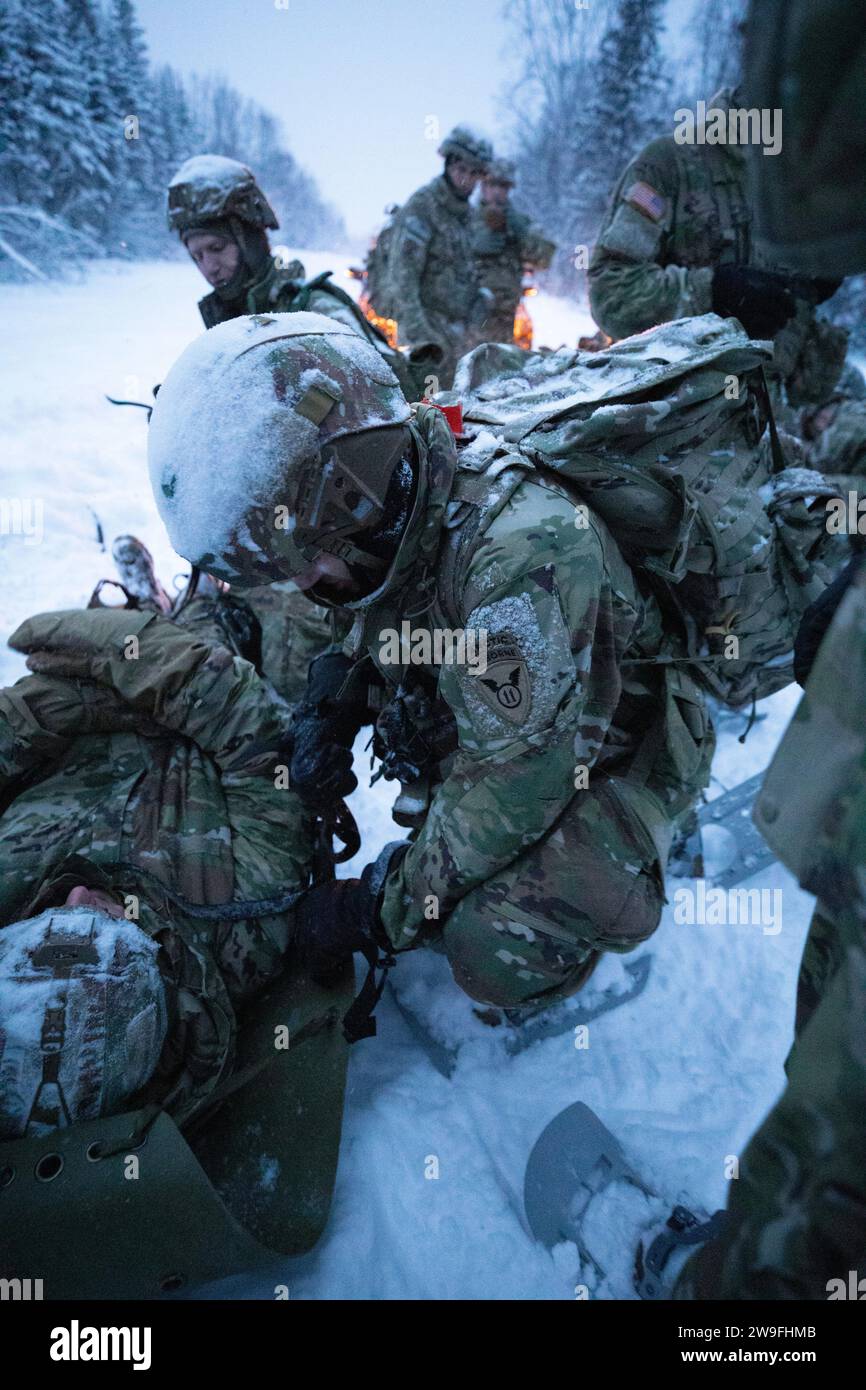 U.S. Soldiers with 1st Squadron, 40th Cavalry Regiment, 2nd Infantry Brigade Combat Team (Airborne), 11th Airborne Division, pack a notional casualty into a skedco during a brigade physical fitness competition at Joint Base Elmendorf-Richardson, Alaska, Dec. 8, 2023. The competition included pulling an ahkio, setting up a 10-man tent, and using a skedco to pull a notional casualty; tasks all Arctic Angels are expected to be proficient in. (U.S. Army photo by Sgt. Avery Cunningham) Stock Photo