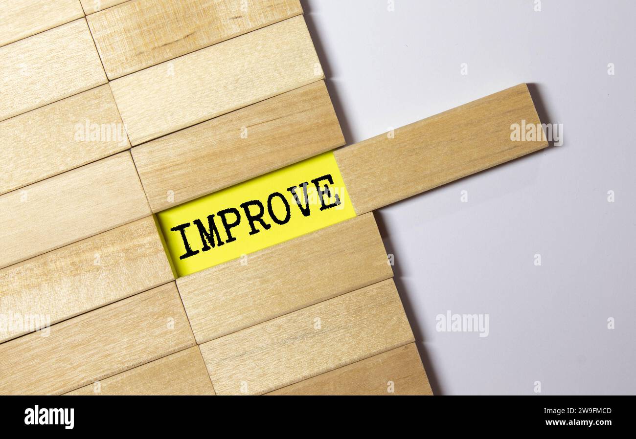 Miniature people paint the word improve on wooden blocks on a white background. Stock Photo