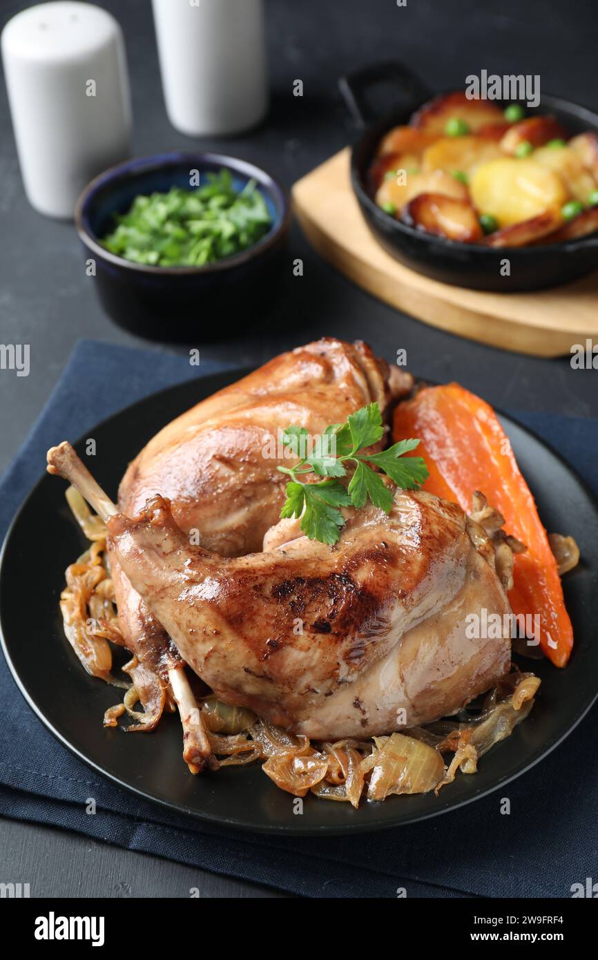 Tasty cooked rabbit meat with vegetables served on black table Stock Photo
