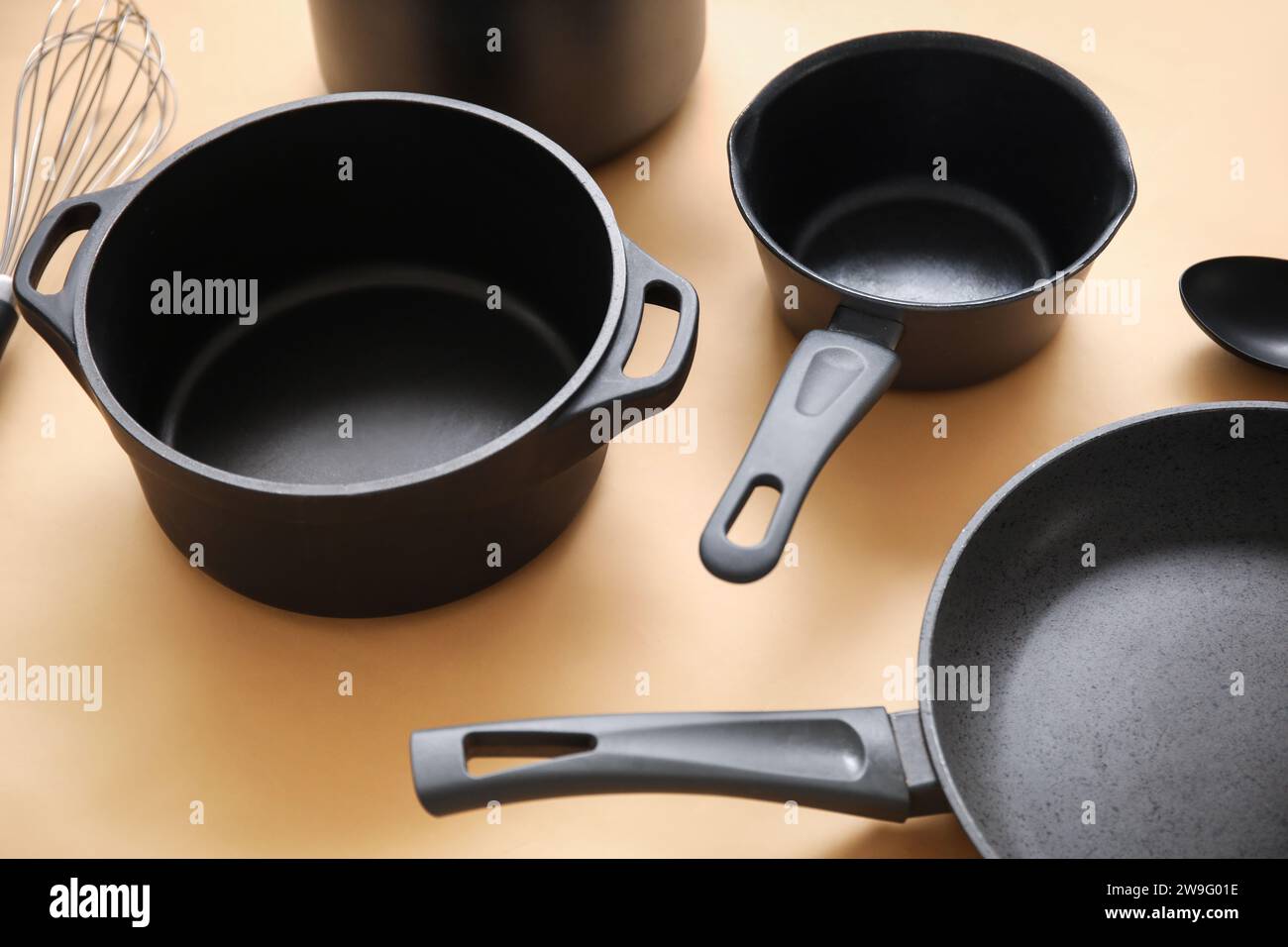 Cooking pots and frying pan on beige background, closeup Stock Photo