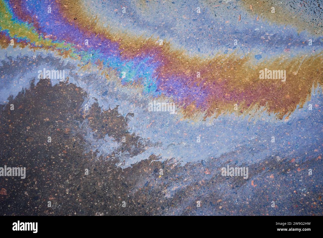 Multicolored poisonous spots of spilled gasoline on wet pavement