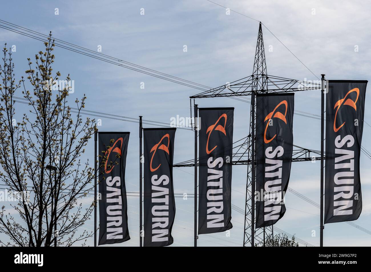 Koblenz, Germany - April 22, 2021: flags with the logo and lettering of the Saturn media retailer in front of a high voltage pylon Stock Photo