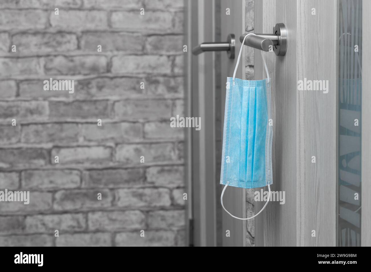 used medical mask hanging on the door handle Stock Photo - Alamy