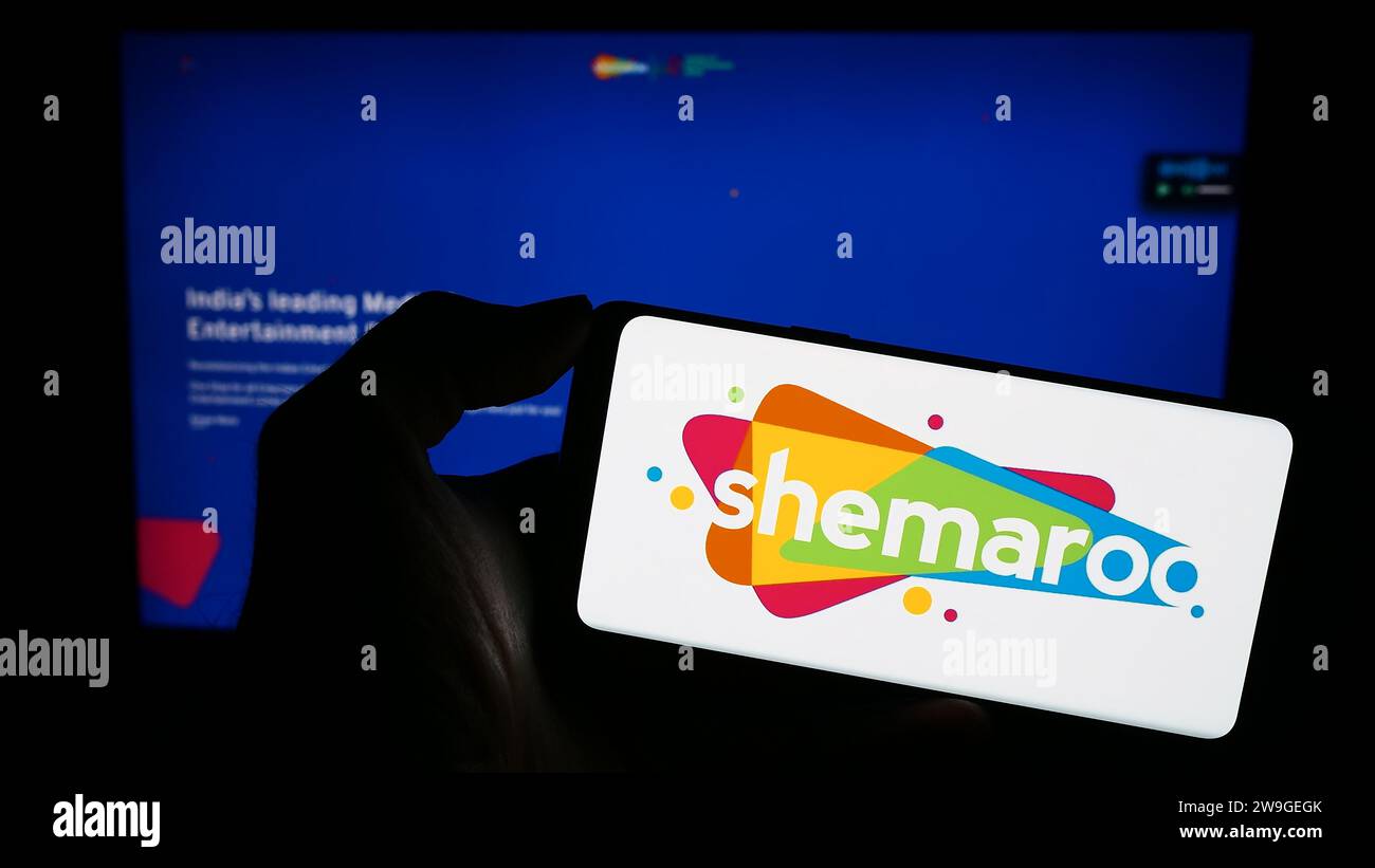 Person holding mobile phone with logo of Indian company Shemaroo Entertainment Ltd. in front of