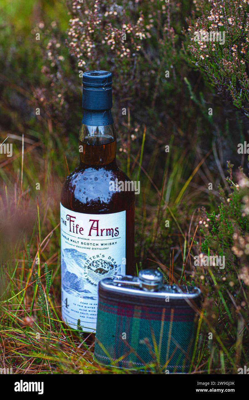 Single Malt Scotch Whisky and Tartan Hip Flask stands on grass in the landscape. Stock Photo