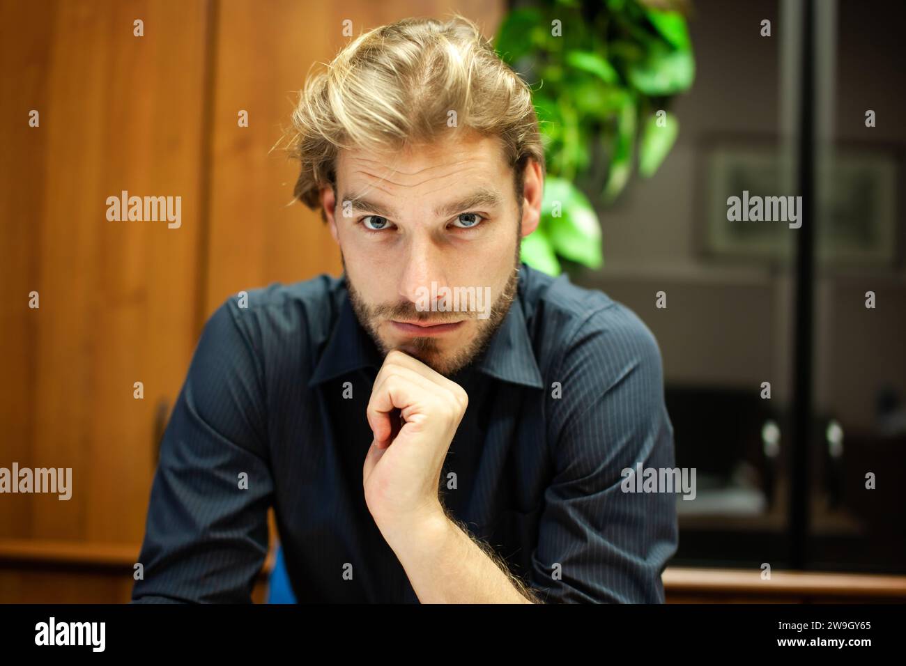Man in a blue shirt with a pensive look on his face Stock Photo