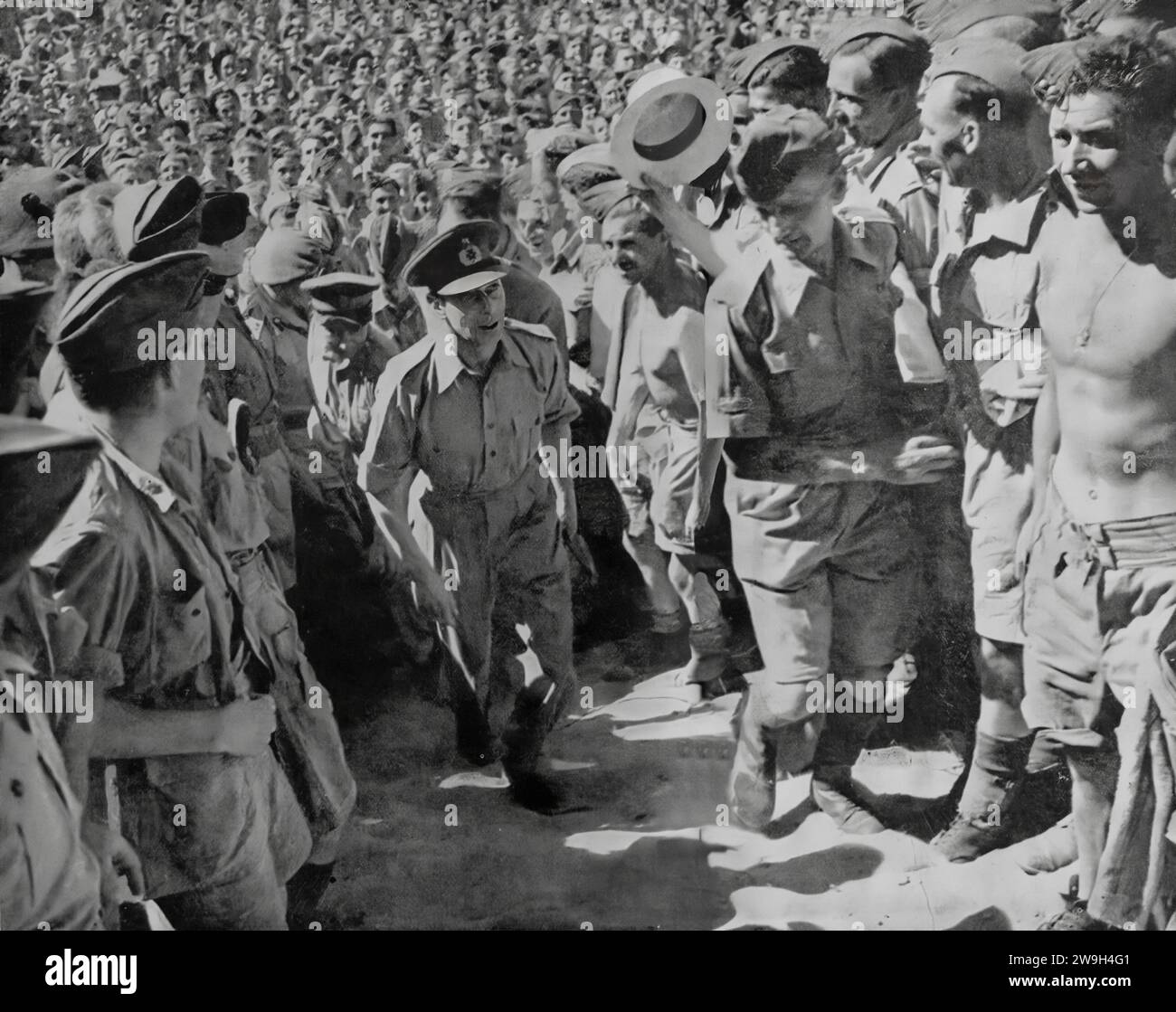 King George VI walking between lines of troops at a convalescent centre in North Africa during the Second World War. It was a long visit in June 1943 during which time he met British and American troops and their military leaders. Stock Photo