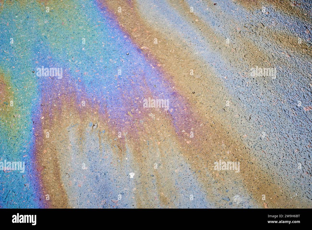 Multicolored poisonous spots of spilled gasoline on wet pavement