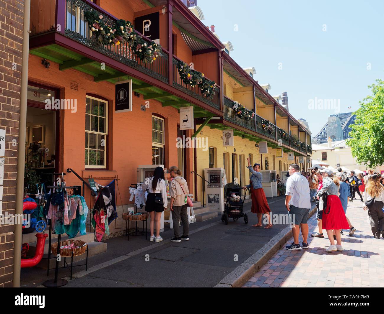 View of tourists and shoppers walking through the colourful shops cafes and market stalls in The Rocks district of Sydney Australia Stock Photo