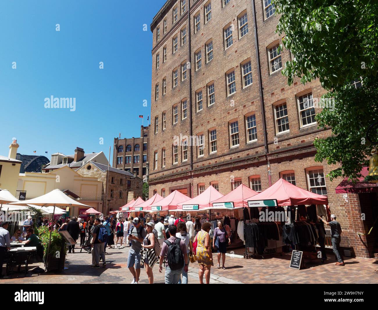 View of tourists and shoppers walking through the colourful shops cafes and market stalls in The Rocks district of Sydney Australia Stock Photo