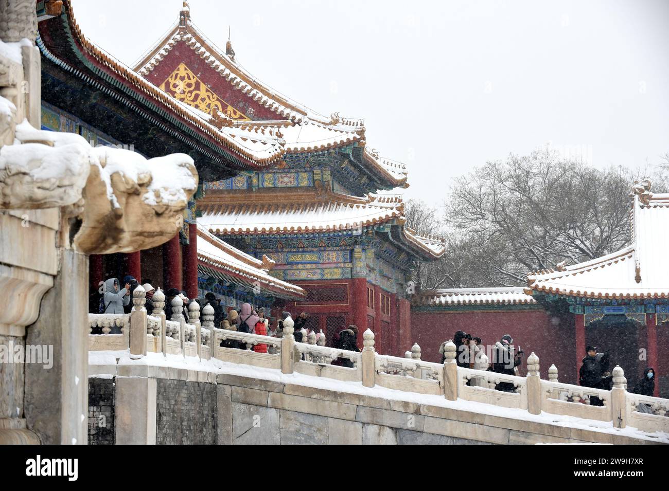 (231228) -- BEIJING, Dec. 28, 2023 (Xinhua) -- Visitors enjoy snow scenery at the Palace Museum in Beijing, capital of China, Dec. 14, 2023.  First created in the Yuan Dynasty (1271-1368), the Beijing Central Axis, or Zhongzhouxian, stretches 7.8 kilometers between the Yongding Gate in the south of the city and the Drum Tower and Bell Tower in the north. Most of the major old-city buildings of Beijing sit along this axis.   Gates, palaces, temples, squares and gardens of the old city are all linked up to the axis. As they witnessed the folk activities along the line from old days to new ones, Stock Photo