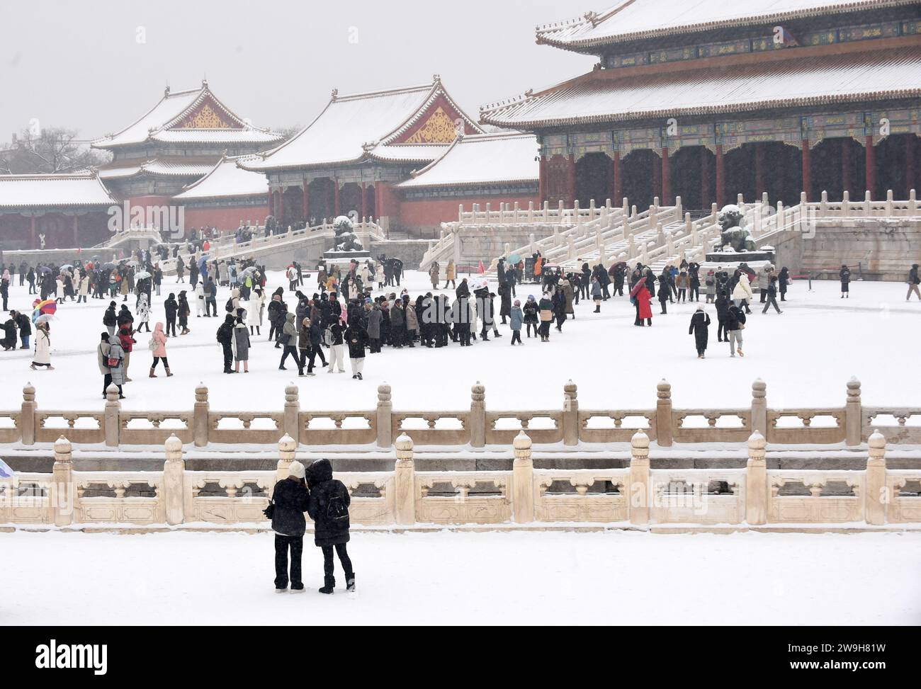 (231228) -- BEIJING, Dec. 28, 2023 (Xinhua) -- Visitors enjoy snow scenery at the Palace Museum in Beijing, capital of China, Dec. 14, 2023. First created in the Yuan Dynasty (1271-1368), the Beijing Central Axis, or Zhongzhouxian, stretches 7.8 kilometers between the Yongding Gate in the south of the city and the Drum Tower and Bell Tower in the north. Most of the major old-city buildings of Beijing sit along this axis. Gates, palaces, temples, squares and gardens of the old city are all linked up to the axis. As they witnessed the folk activities along the line from old days to new ones, Stock Photo
