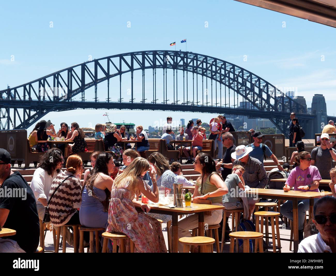 View of diners on the concourse at the Sydney Opera House with the famous Sydney Harbour Bridge in the background Stock Photo