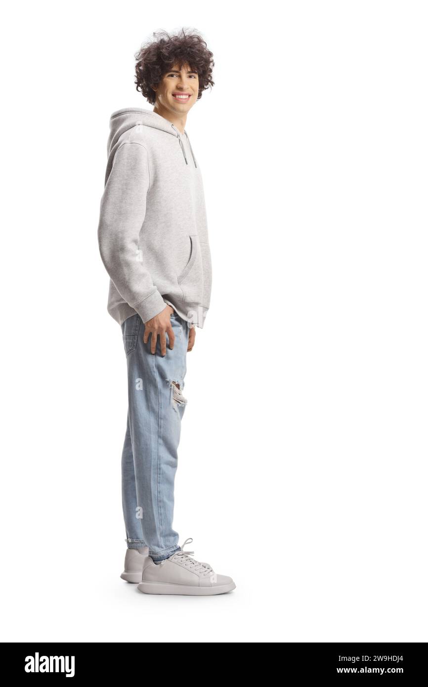 Full length portrait of a cute tall guy with curly hair in a gray hoodie and jeans isolated on white background Stock Photo