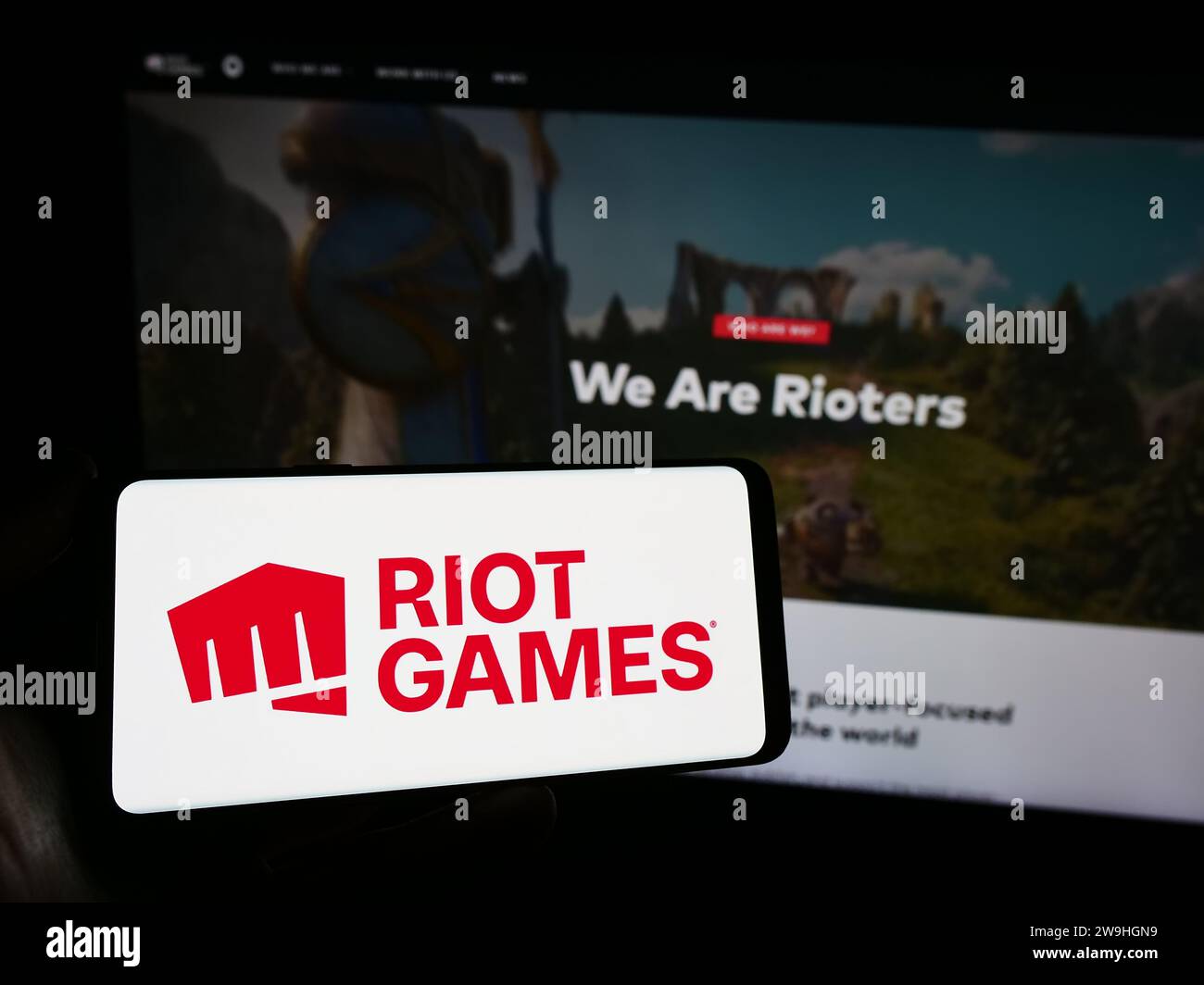 Person holding smartphone with logo of US video game development company Riot Games Inc. in front of website. Focus on phone display. Stock Photo