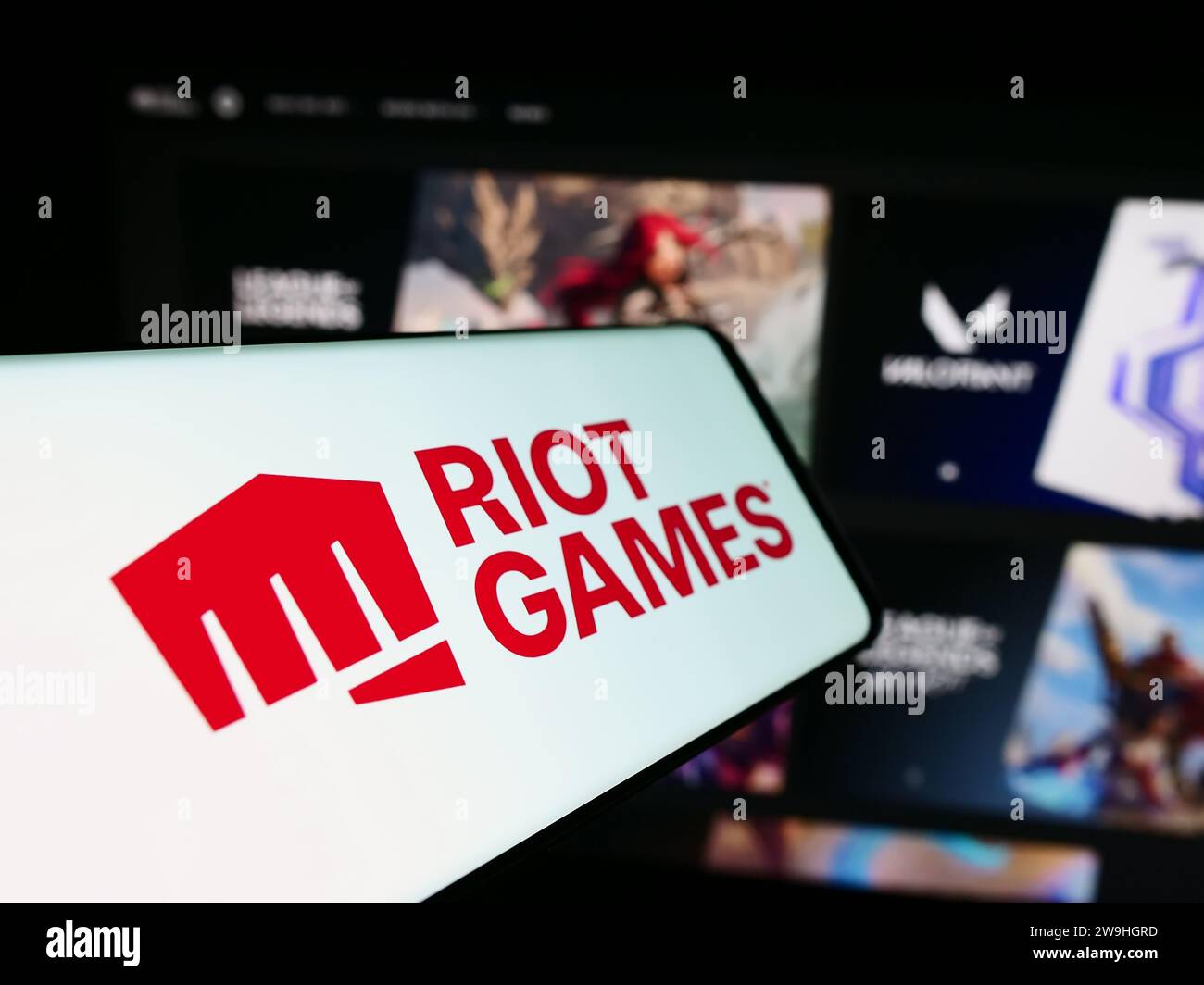 Cellphone with logo of American video game development company Riot Games Inc. in front of website. Focus on center-left of phone display. Stock Photo