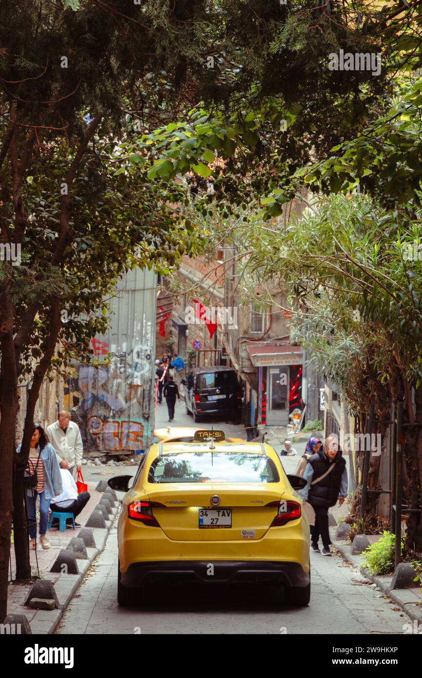 Yellow taxi on the street in Beyoğlu district of Istanbul, Turkey, surrounded by trees in spring Stock Photo