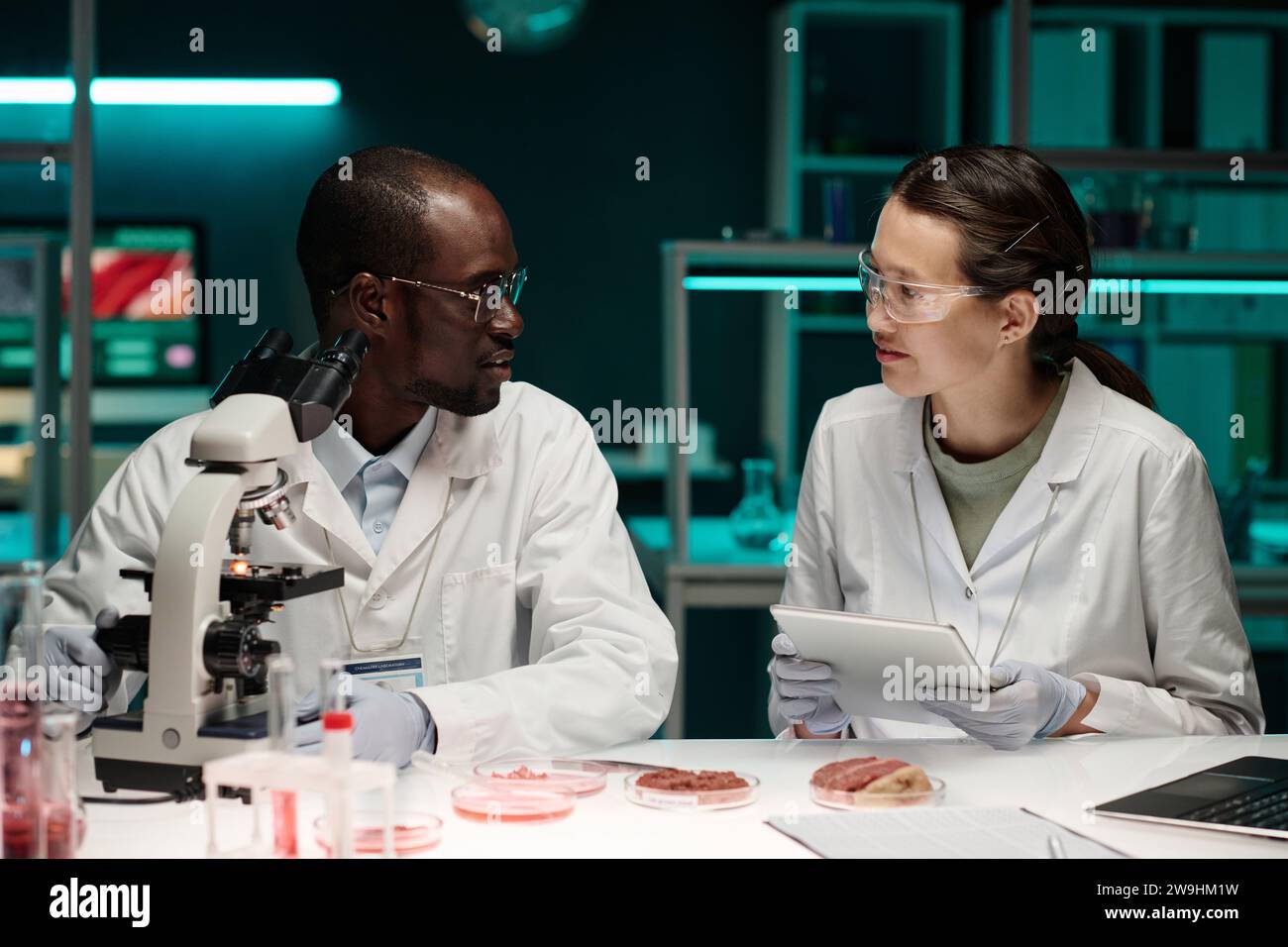 African american researcher talking to his asian colleague during their work on meat alternatives Stock Photo
