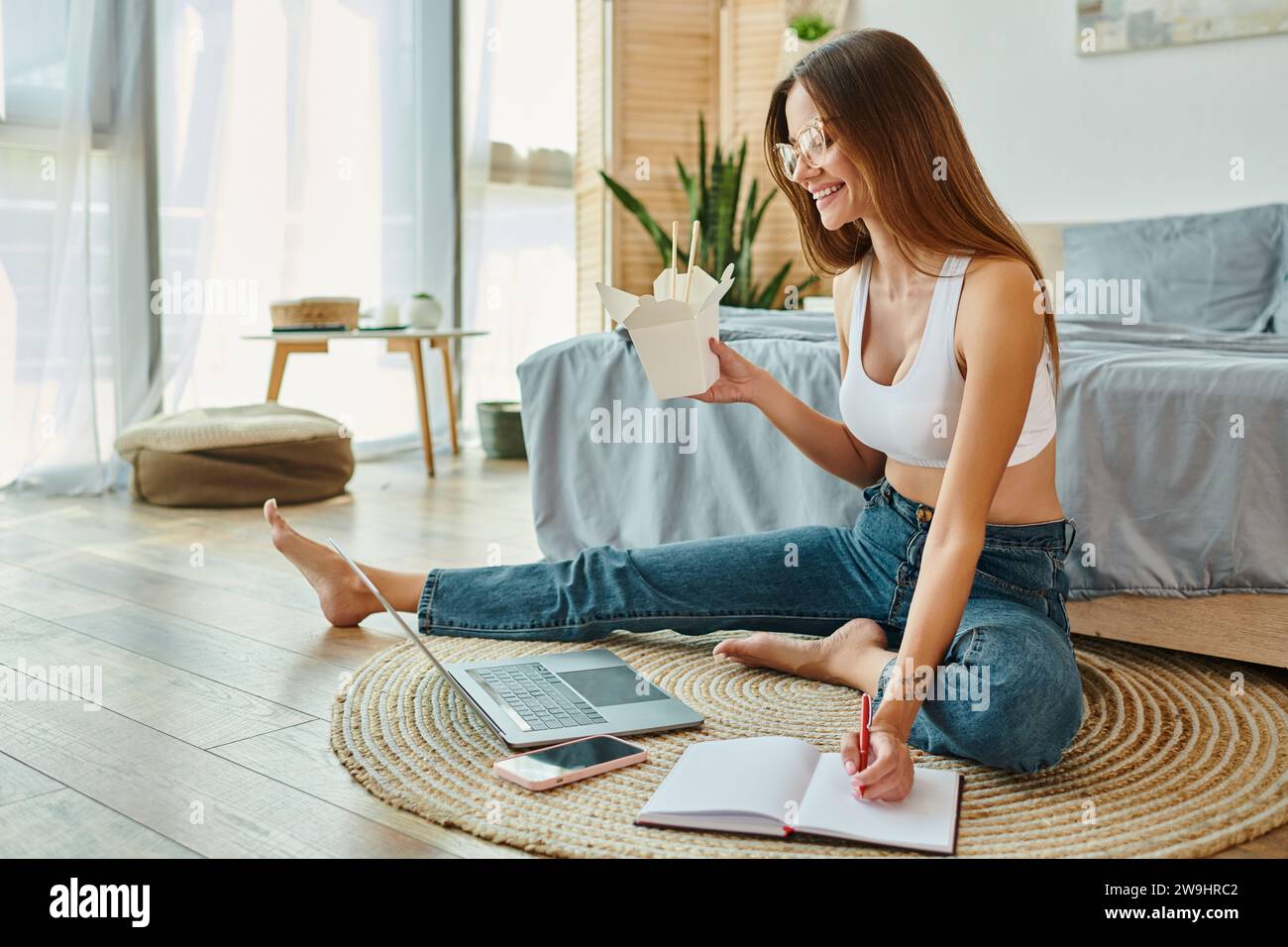 cheerful appealing woman with glasses taking notes while working