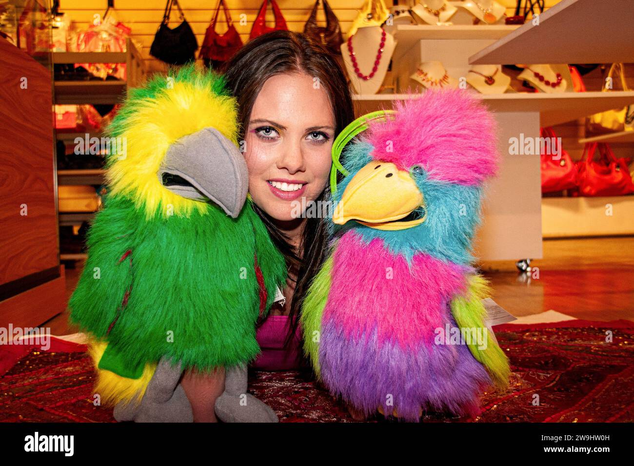 Inside a boutique store, a glamorous woman has fun modelling while playing with glove puppets in  Dundee, Scotland Stock Photo