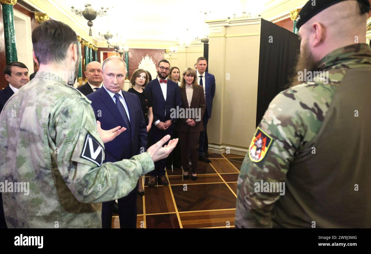 Moscow, Russia. 27th Dec, 2023. Russian President Vladimir Putin, center, listens to service members during a tour of an exhibition dedicated to the key events of the outgoing Year of Teachers and Mentors at the Kremlin, December 27, 2023 in Moscow, Russia. Credit: Gavriil Grigorov/Kremlin Pool/Alamy Live News Stock Photo