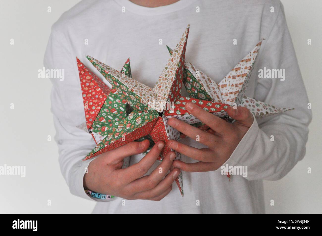 A studio shot of a child holding a collection of origami stars made from festive origami paper Stock Photo