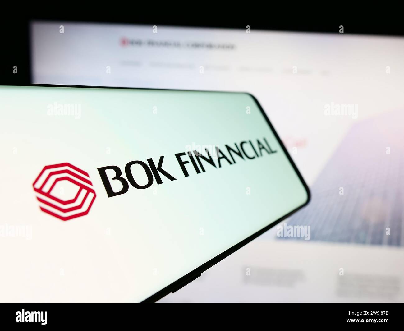 Smartphone with logo of American financial services company BOK Financial Corporation in front of website. Focus on center-left of phone display. Stock Photo