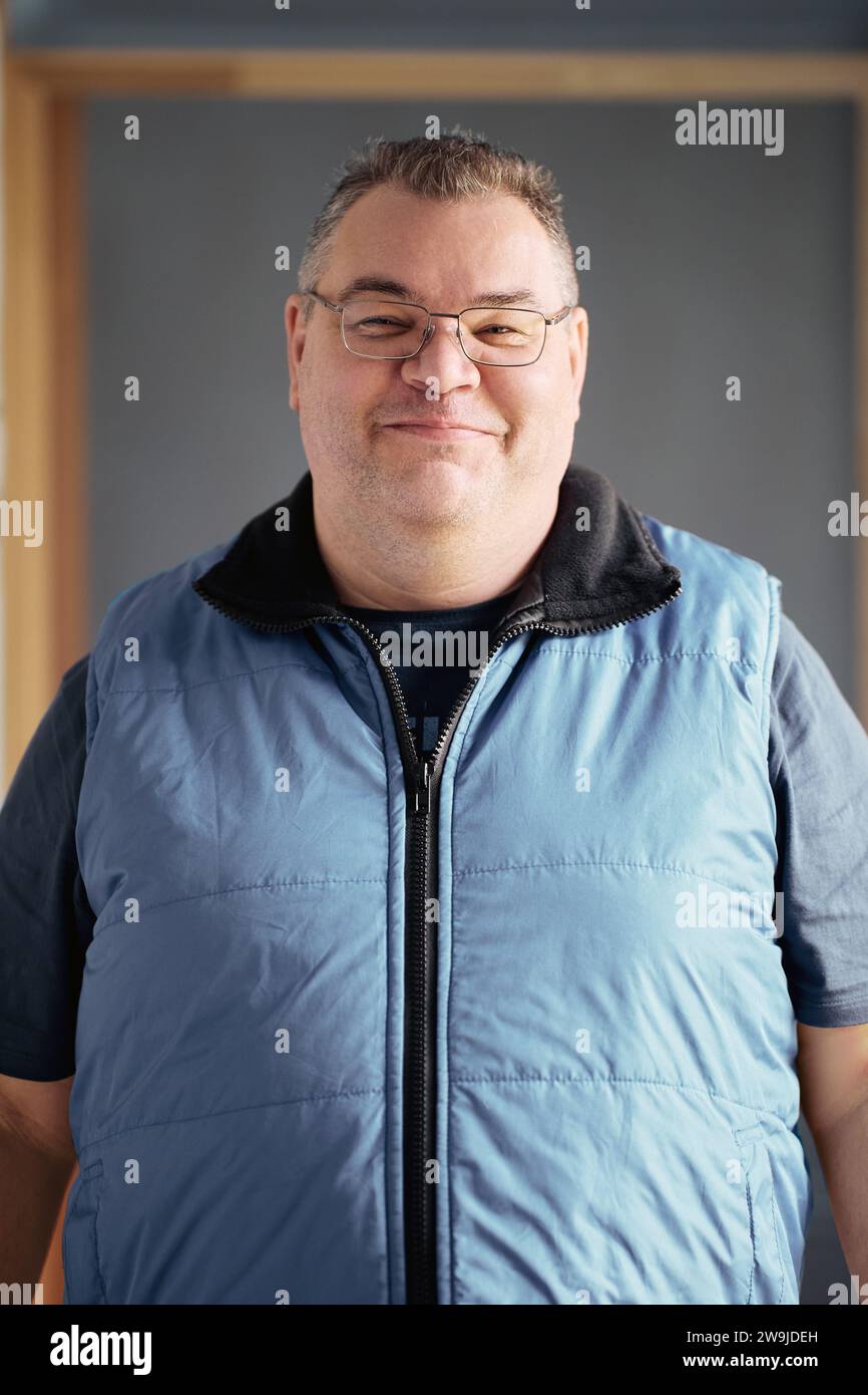 Heavily built European man wearing glasses with short haircut stands