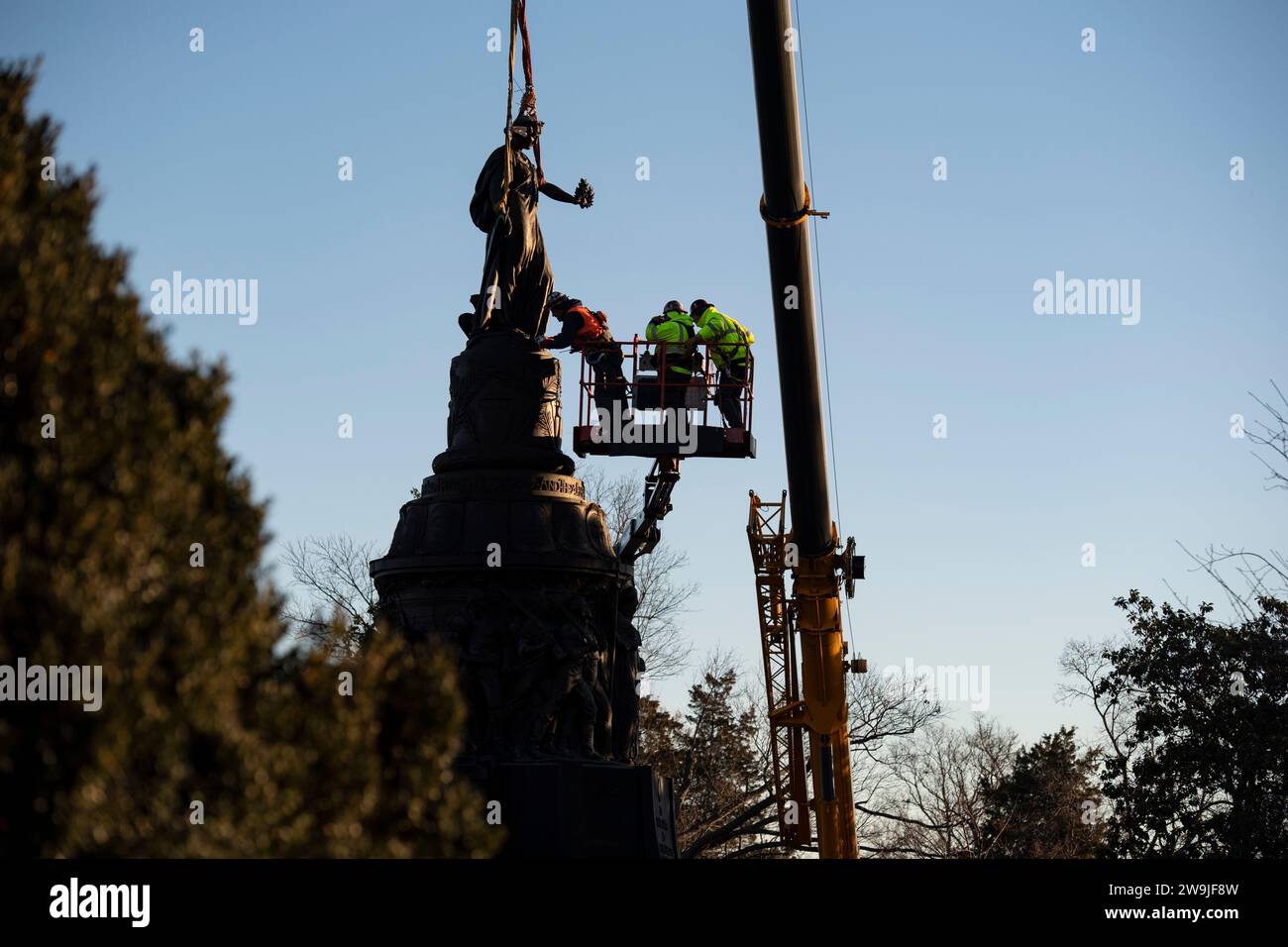 Arlington, United States of America. 20 December, 2023. Workers attach webbing to the bronze statue on the Confederate Memorial in Section 16 of Arlington National Cemetery before removal by crane, December 20, 2023 in Arlington, Virginia. The memorial honoring members of the Confederate States of America is being moved to New Market Battlefield State Historic Park.  Credit: Elizabeth Fraser/U.S. Army/Alamy Live News Stock Photo