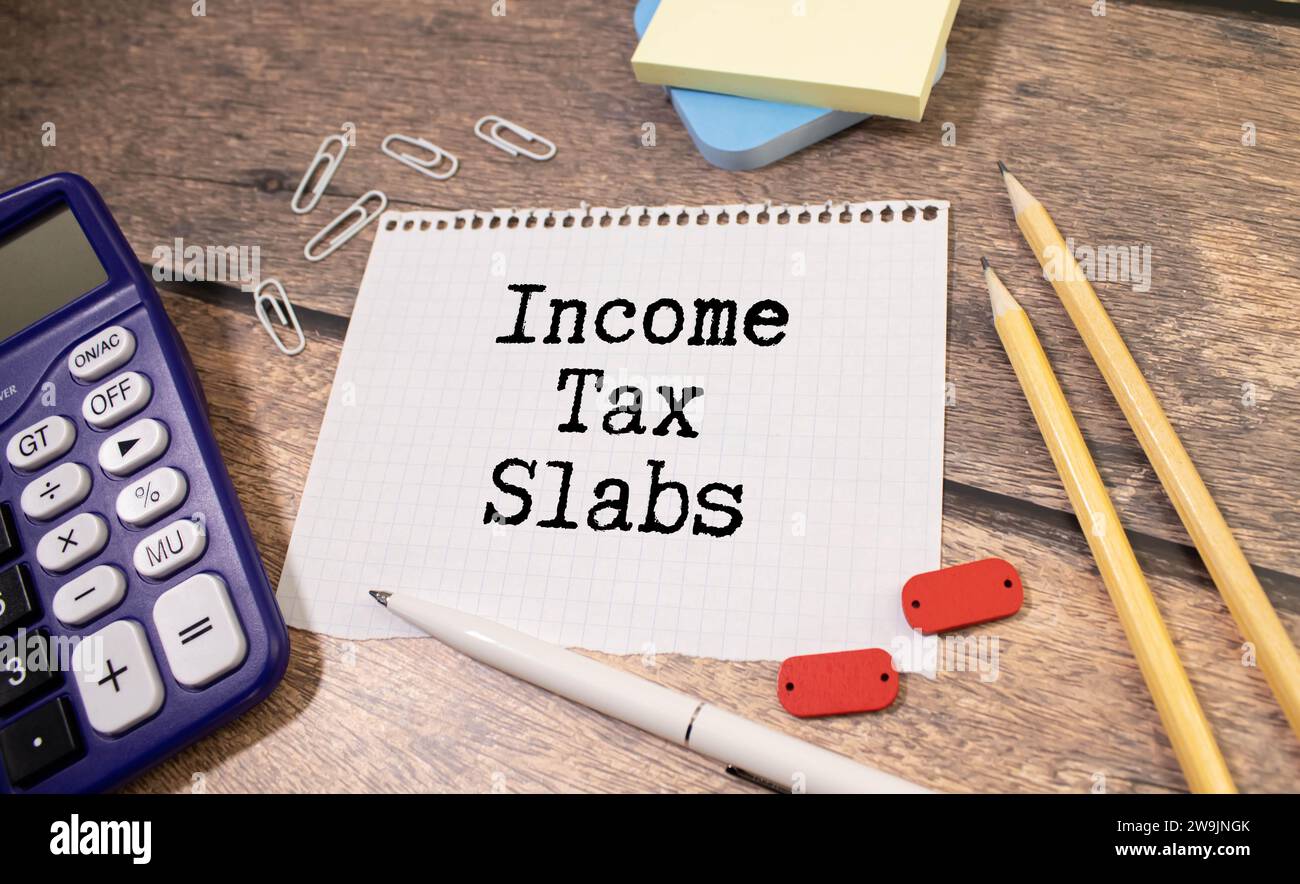 Income Tax Slabs inscription on white card. Workplace background, top view Stock Photo