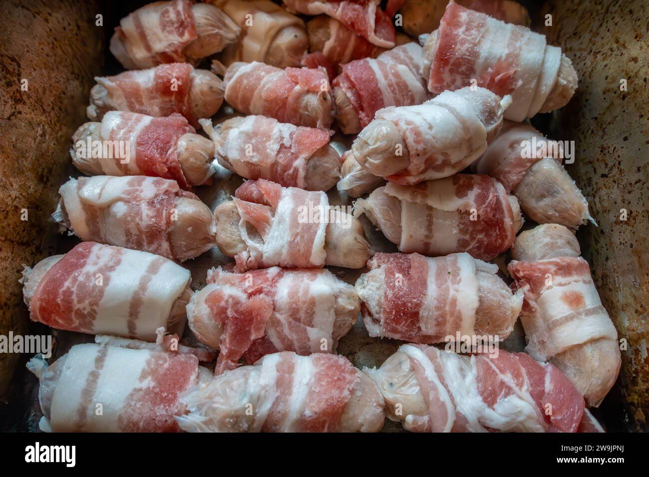 Chipolata sausages wrapped in bacon or 'pigs in blankets' in a baking