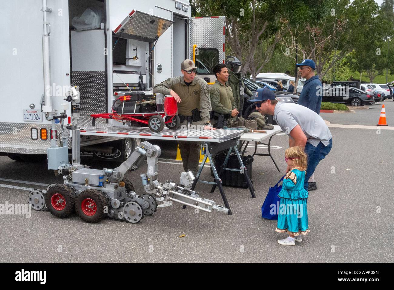 A father and daughter contemplate a a police robot for use in dangerous