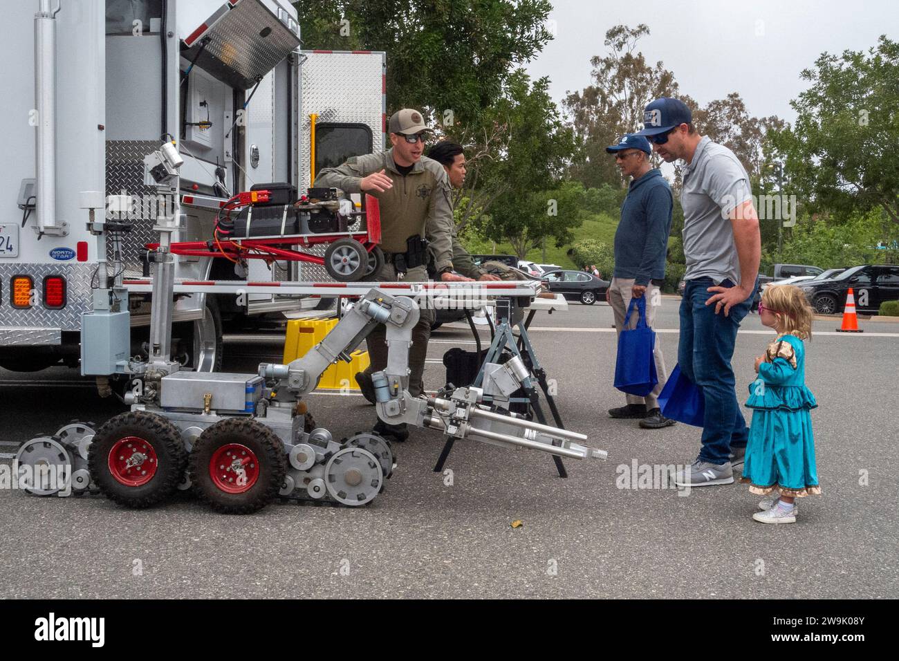 A father and daughter contemplate a a police robot for use in dangerous