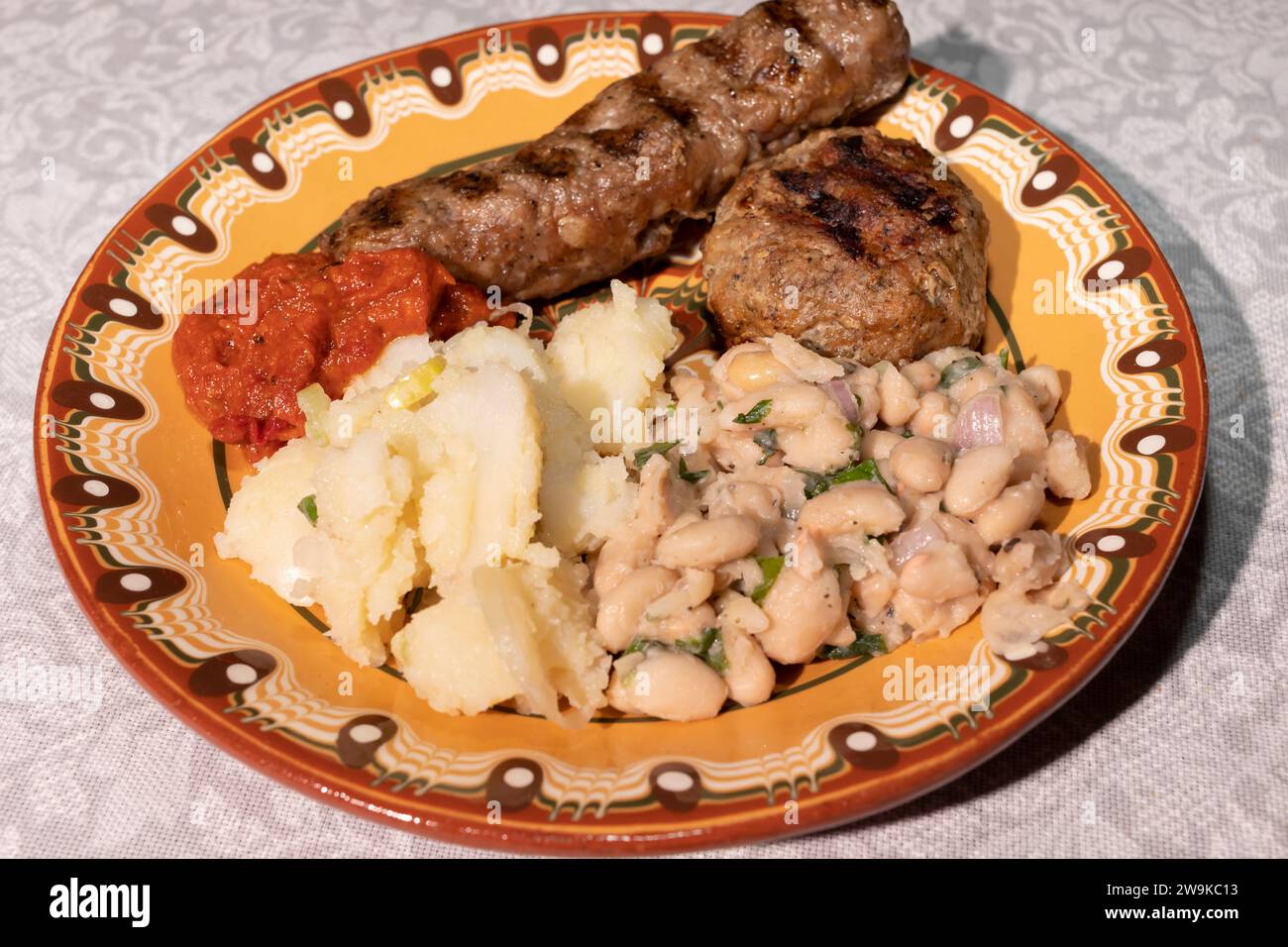 Closeup Plate With Traditional Bulgarian Food. Mashed Potato, White Beans, Haricot, Vegetable Relish Ljutenica, Grilled Minced Meat With Spices Stock Photo