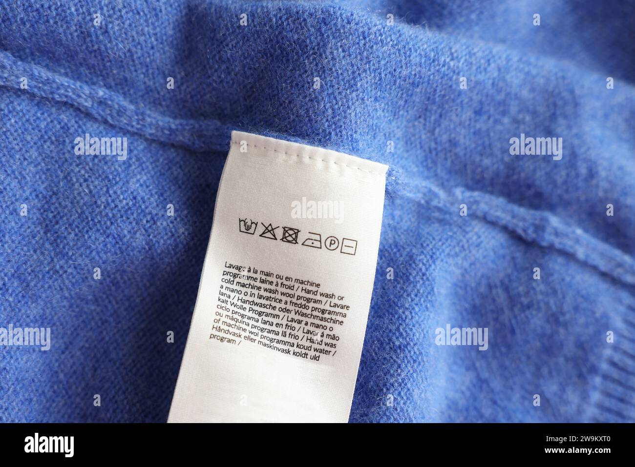 Clothing label in different languages on blue garment, top view Stock ...