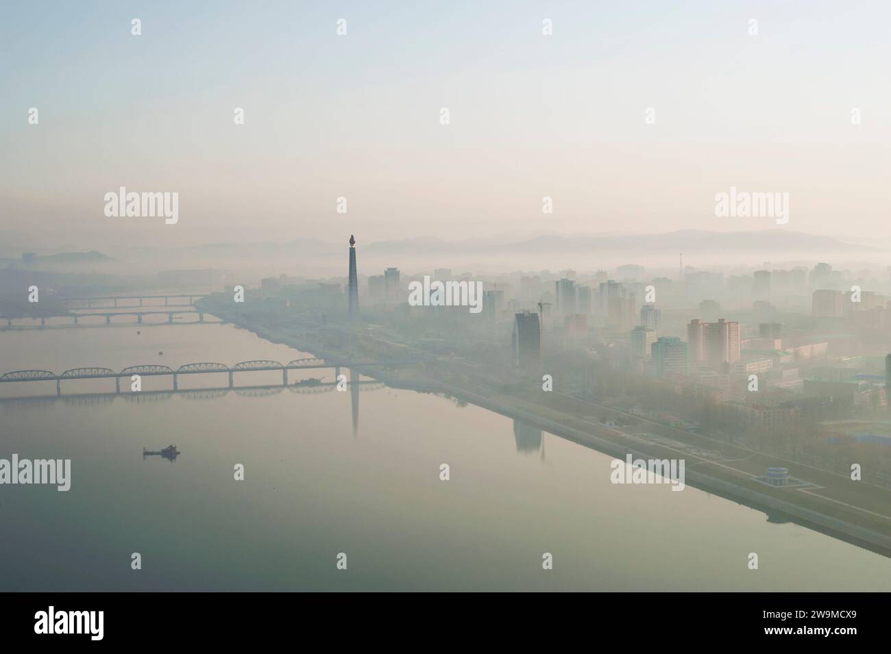 The view of the Taedong River and Juche Tower in Pyongyang in North Korea during a misty early morning sunrise. Stock Photo