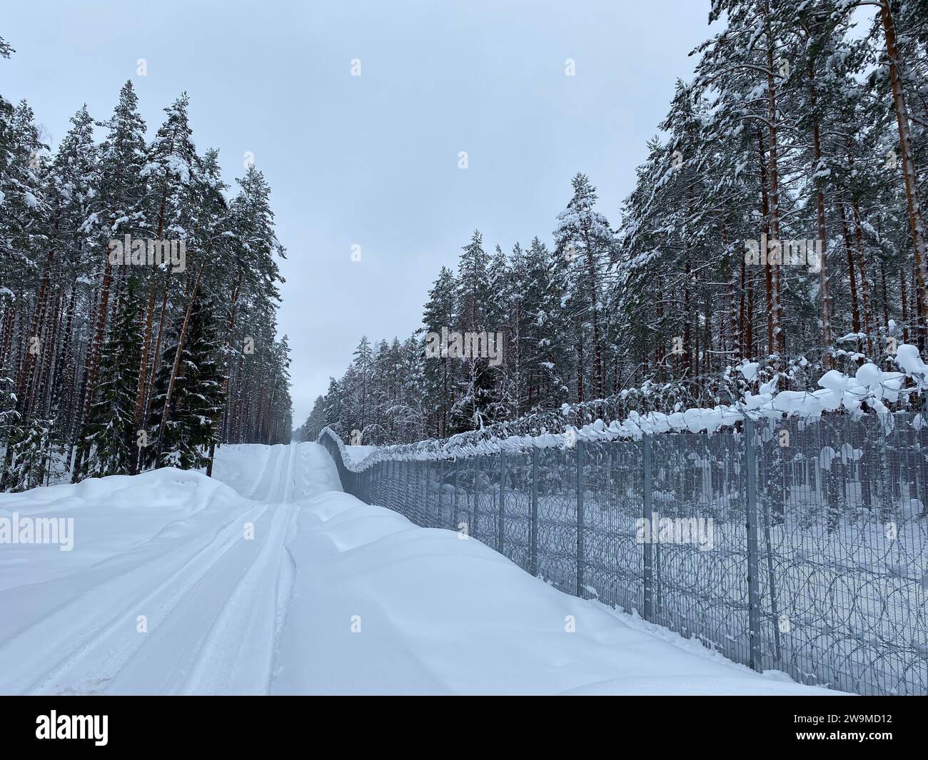 Silene, Latvia. 13th Dec, 2023. The road at the border fence on the Latvian-Belarusian border is covered in deep snow. Latvia has an approximately 172-kilometer-long border with Russia's close ally Belarus, which is part of the EU's external border. (to dpa 'Latvia: fence on border with Belarus nearing completion') Credit: Alexander Welscher/dpa/Alamy Live News Stock Photo